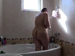 امرأة سمينة جميلة تبتل في الحمام مع رغوة الصابون